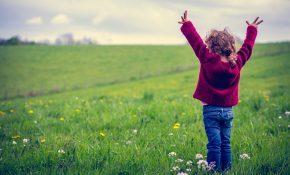 Enfant levant les bras dans un pré verdoyant