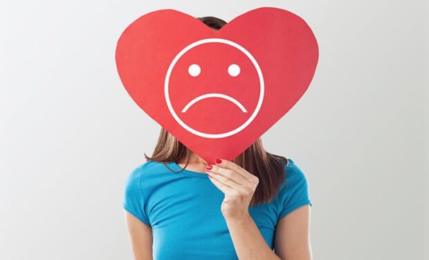 Jeune fille avec un panneau en coeur triste