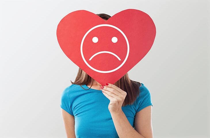 Jeune fille avec un panneau en coeur triste