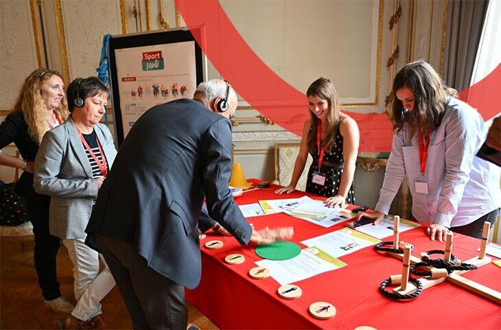 Un homme quinquagénaire et en costume est en train de tester ses réflexes avec un petit jeu présenté sur un stand prévention