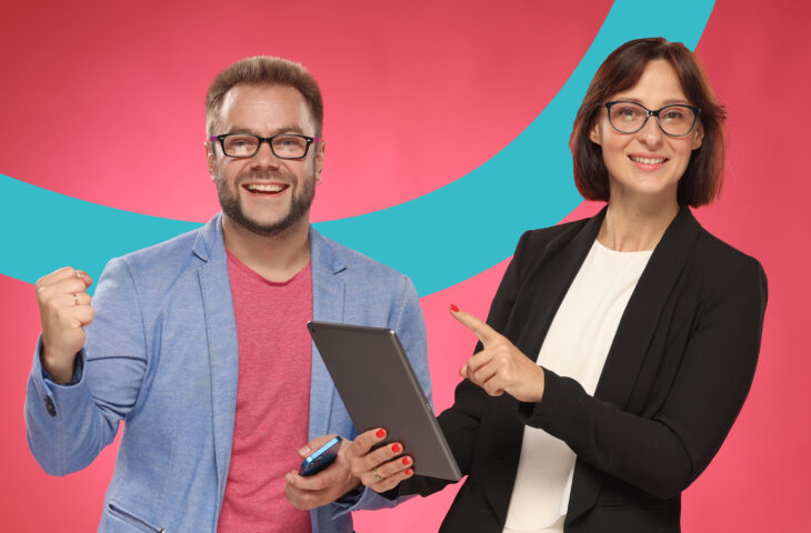 Un homme et une femme, des collègues de travail, sourient et ont l'air victorieux.