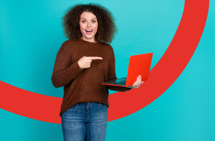 Sur un fond coloré, une femme souriante tient son ordinateur portable dans une main et de l'autre, le pointe du doigt.